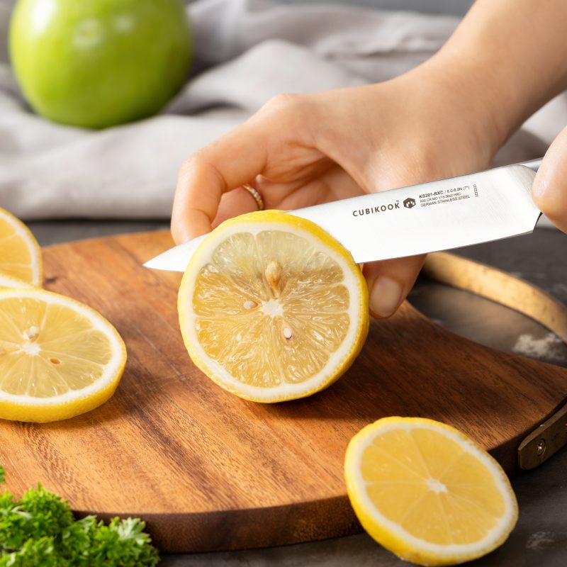 slicing lemon on a cutting board by an utility knife